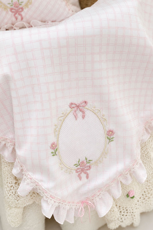 Detalle de toquilla Picnic Lace para bebé con bordado floral rosa y encaje
