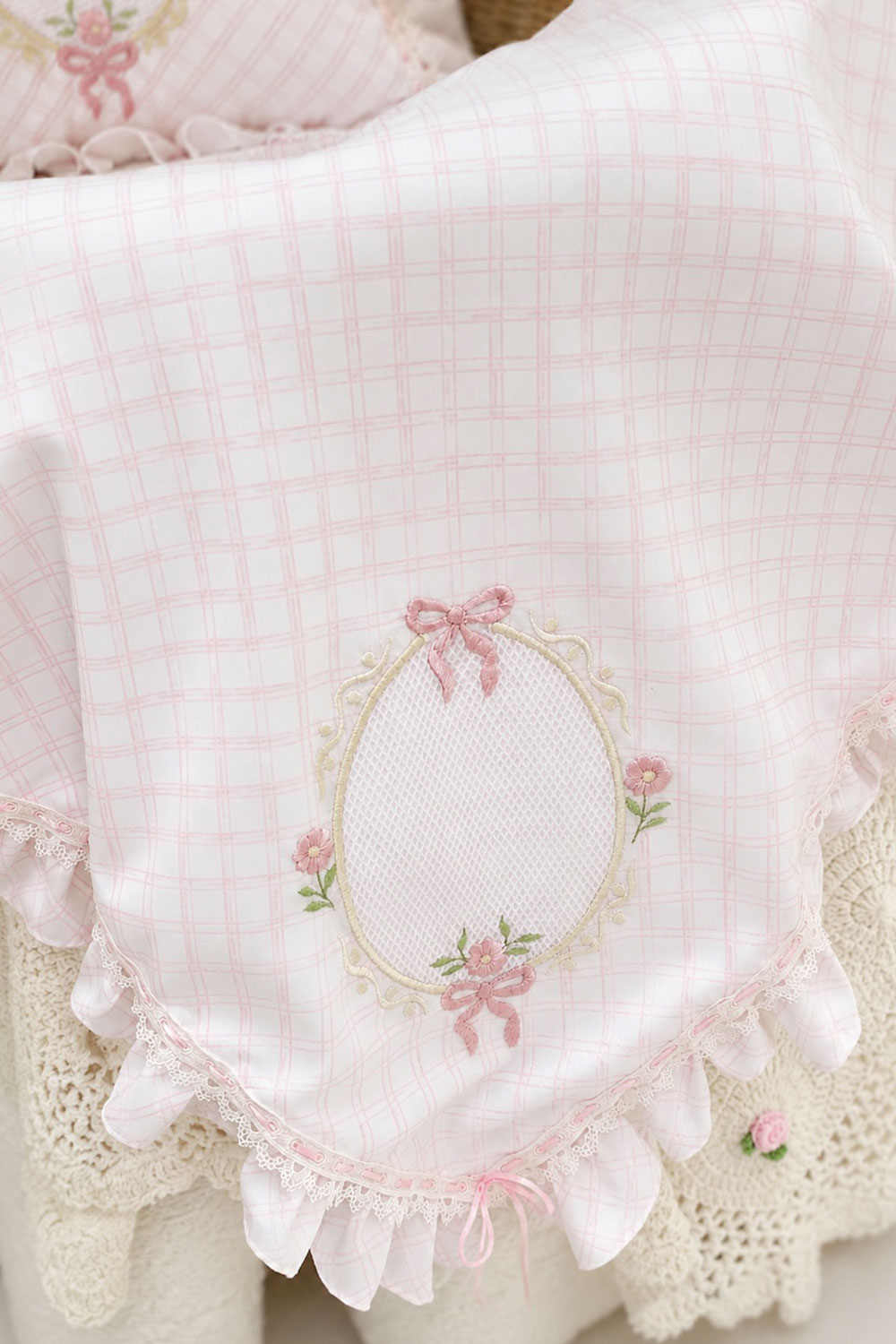 Detalle de toquilla Picnic Lace para bebé con bordado floral rosa y encaje